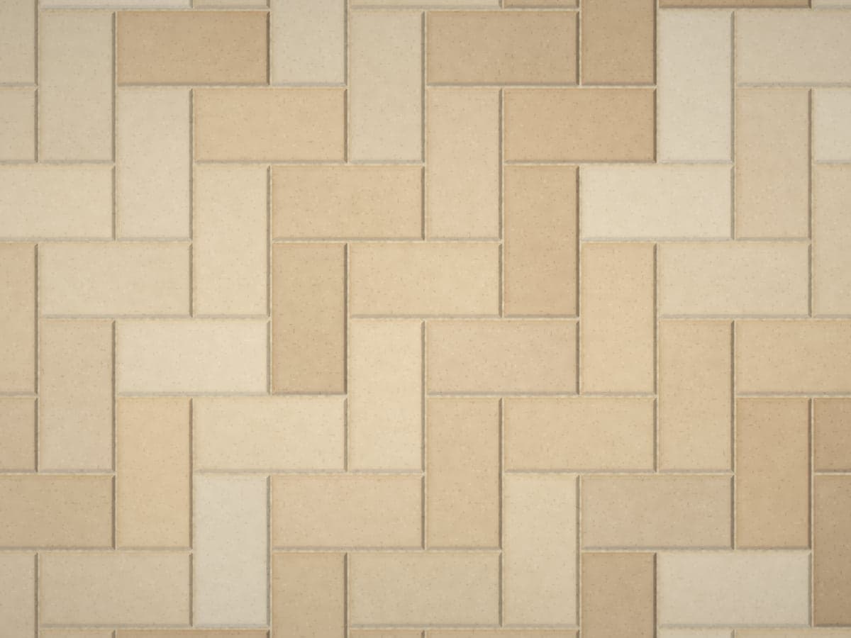 Tan and sand-colored concrete pavers laid in a 90-degree herringbone pattern.