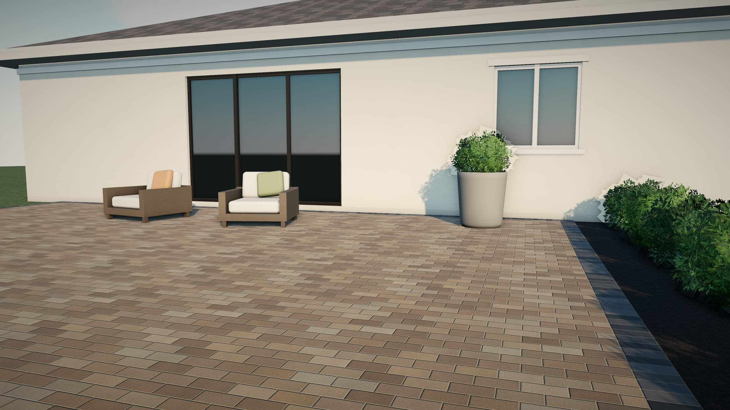Sealed running-bond paver patio with a charcoal border, two lounge chairs, a planter, and a planted bed along the edge.